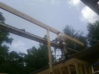 Carpenter setting a ridge beam over a new addition frame — Ice Dam Removal by Roofing Brothers in Lawndale