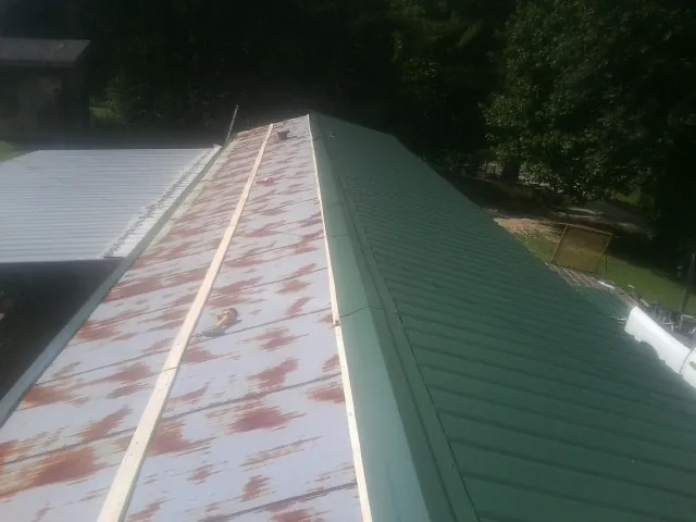 Old rusted panels beside newly installed green metal roofing — Wind Damage Roof Repair by Roofing Brothers in Lawndale