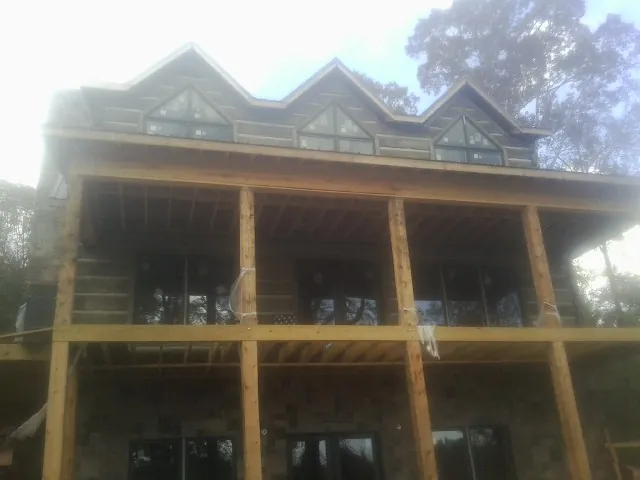 Dormers and porch framing on a large log home under construction — Roof Coating work by our crew in Lawndale
