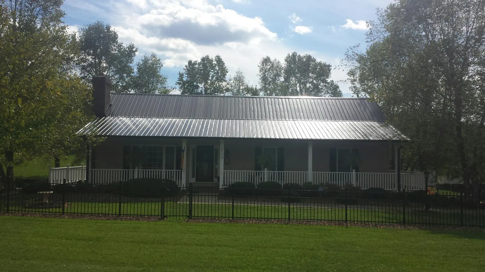 Gray metal roof on a brick ranch with a full width front porch — Gutter Guard Installation work by our crew in Lawndale
