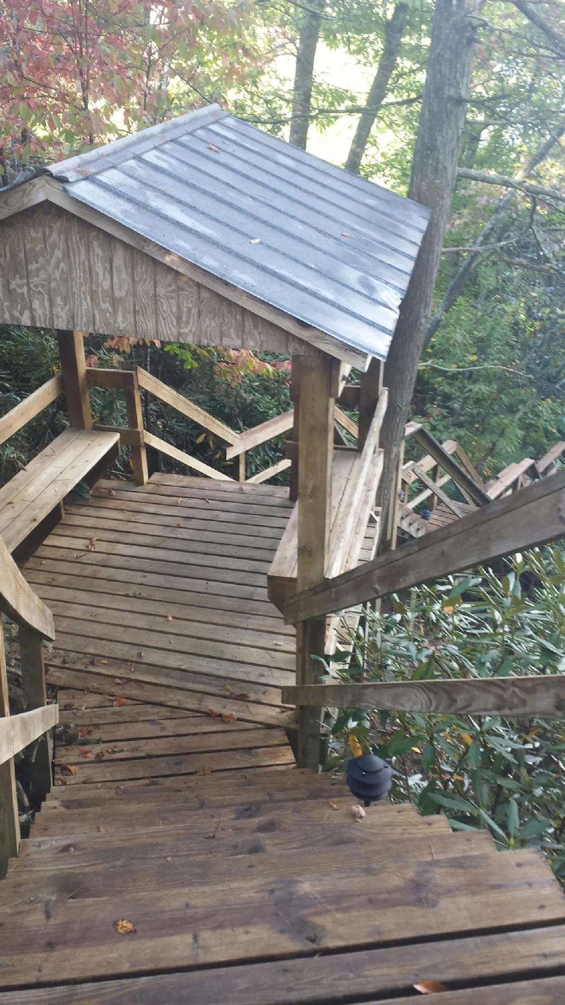 Metal roofed shelter over wooden steps on a wooded walkway — Skylight Repair & Installation work by our crew in Lawndale
