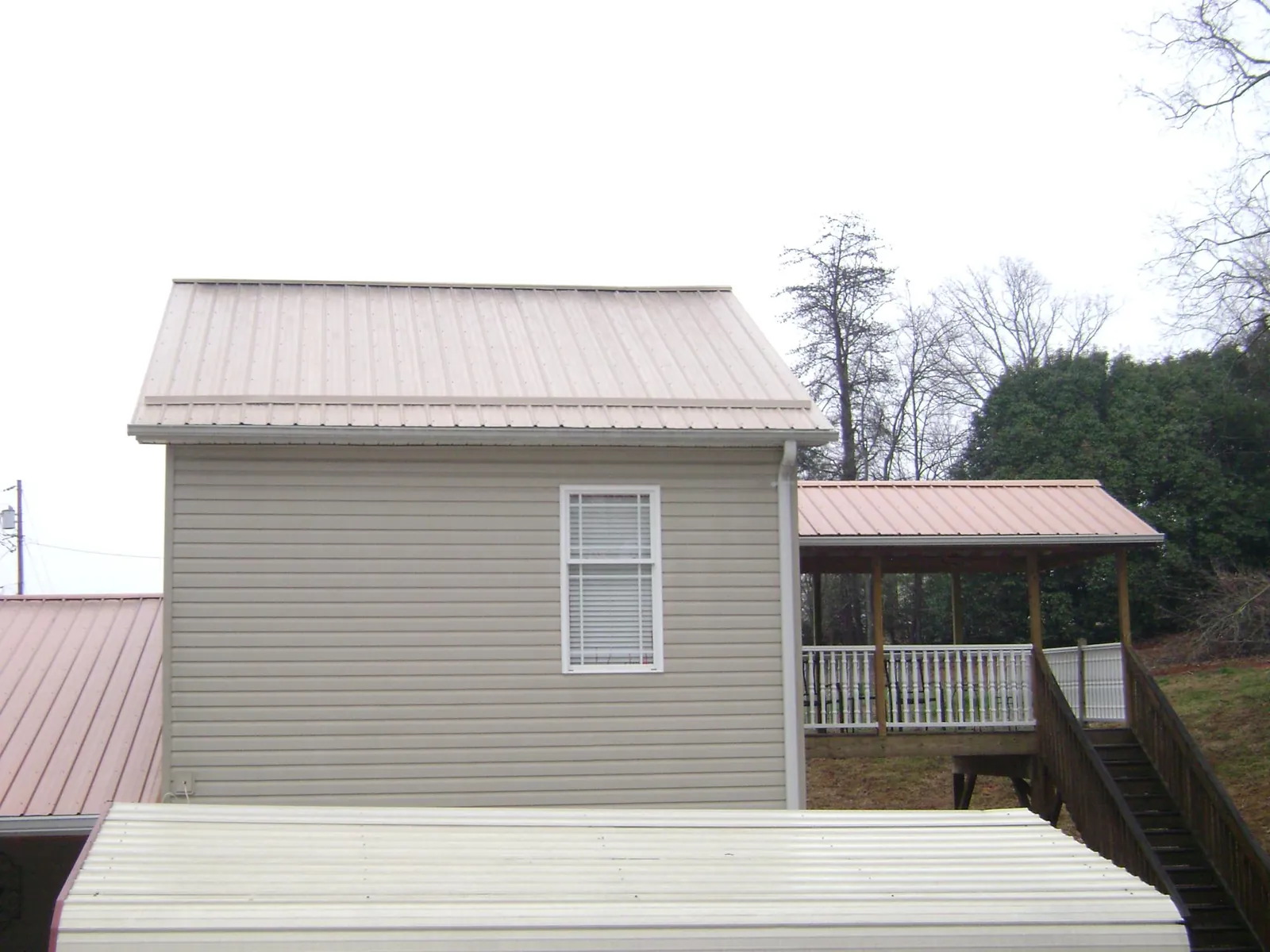 Tan metal roofs on a two story addition and attached porch, from a Roof Replacement job in Lawndale